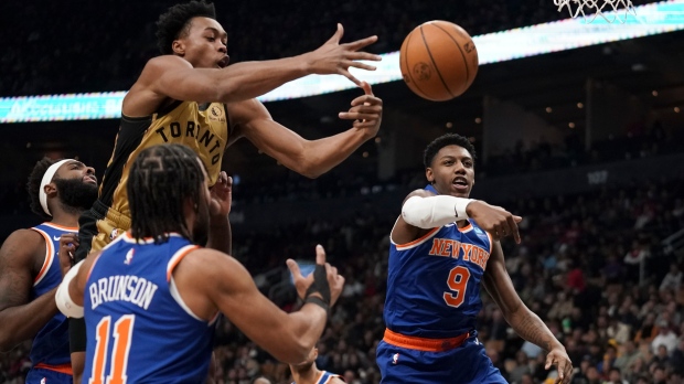 Toronto Raptors forward Scottie Barnes (4) jumps to shoot while being guarded by New York Knicks guard RJ Barrett (9), right, and guard Jalen Brunson (11) during first half NBA basketball action in Toronto, Friday, Dec. 1, 2023. THE CANADIAN PRESS/Arlyn McAdorey