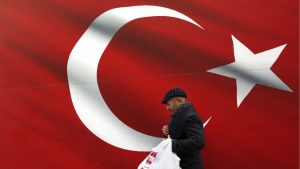 A man walks by a Turkish flag in Ankara, Turkiye, Sunday, March 31, 2019. (AP Photo/Ali Unal/File)
