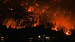 The McDougall Creek wildfire burns on the mountainside above houses in West Kelowna, B.C., on Friday, August 18, 2023. THE CANADIAN PRESS/Darryl Dyck