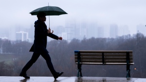 The Toronto skyline sits shrouded in fog as a man walks in the rain on Thursday December 28, 2023.  THE CANADIAN PRESS/Frank Gunn