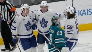 Toronto Maple Leafs right wing William Nylander, top middle, is congratulated by center John Tavares, left, and left wing Tyler Bertuzzi (59) after scoring a goal past San Jose Sharks goaltender Mackenzie Blackwood (29) during the third period of an NHL hockey game in San Jose, Calif., Saturday, Jan. 6, 2024. (AP Photo/Jeff Chiu)