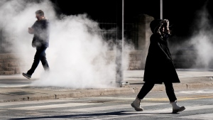 People walk through steam in the cold winter weather in Toronto, on Friday, February 3, 2023. THE CANADIAN PRESS/Nathan Denette