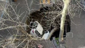 Two people suffered minor injuries after two cars were swallowed by a giant sinkhole in Naples, Italy.