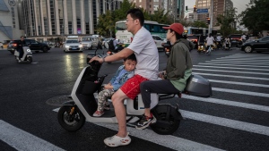 A boy riding with his parents on a scooter in Beijing, China, on September 13, 2023. (Kevin Frayer/Getty Images via CNN Newsource)
