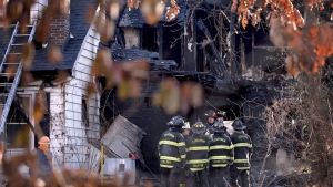 Firefighters gather around a burned out section of a home after they extinguished the flames of house fire in Ferguson Mo., on Monday, Feb. 19, 2024. (David Carson/St. Louis Post-Dispatch via AP)