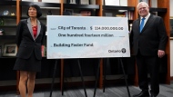Toronto Mayor Olivia Chow, left, and Ontario Premier Doug Ford, right, pose for a photo with a cheque to the City of Toronto for housing development at Toronto City Hall, in Toronto on Thursday, Feb. 22, 2024. THE CANADIAN PRESS/Arlyn McAdorey