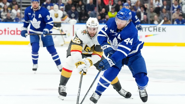 Toronto Maple Leafs' Morgan Rielly battles for the puck with Vegas Golden Knights' Michael Amadio during first period NHL hockey action in Toronto, on Tuesday, February 27, 2024.THE CANADIAN PRESS/Chris Young