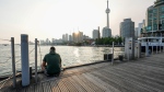 FILE - A man sits on a pier near the Harbourfront Centre in Toronto, on Wednesday, June 28, 2023. THE CANADIAN PRESS/Andrew Lahodynskyj 