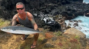 Mike Moody, as shown in this handout image, was fishing off the Big Island of Hawaii early Sunday when a Canadian tourist drove his rented Jeep off a cliff. Moody poses with his catch of the day and the Canadian man's mangled Jeep in the background in this undated photo. THE CANADIAN PRESS/HO- **MANDATORY CREDIT**
