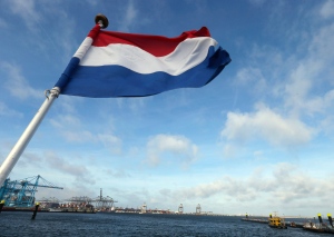 The Dutch flag flies on the stern of a ship as it passes a container terminal, rear, in the harbor of Rotterdam, Netherlands, Tuesday, Sept. 11, 2018. (AP Photo/Peter Dejong)