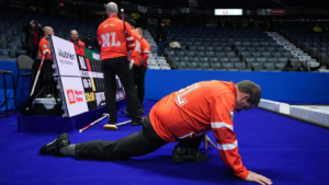 Newfoundland and Labrador lead Alex Smith, front, stretches before playing Team Alberta-Bottcher during the Brier, in Regina, on Saturday, March 2, 2024. Smith is playing in his first Brier since 1989. (Darryl Dyck / The Canadian Press)