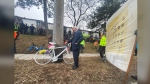 A relative of late cyclist Bill Petropoulos stands next to a ghost bike memorial that was installed in his honour on March 3. (Joey Schwartz photo)