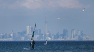 A windsurfer cuts through the waves along Lake Ontario overlooking the City of Toronto skyline on a warm winter day in Mississauga, Ont., Friday, Feb. 9, 2024. THE CANADIAN PRESS/Nathan Denette