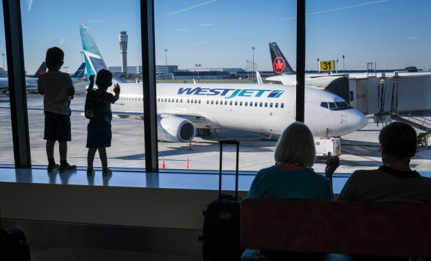 Young boys look out at Air Canada and WestJet planes at Calgary International Airport on August 31, 2022. THE CANADIAN PRESS/Jeff McIntosh
