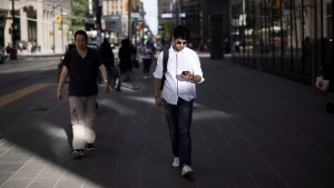 A man looks down at his cell phone while walking though downtown Toronto, on Tuesday, June 12, 2018.THE CANADIAN PRESS/Chris Young 