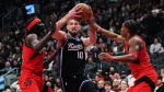 Sacramento Kings forward Domantas Sabonis (10) drives between Toronto Raptors forward Mouhamadou Gueye (left) and guard Jahmi'us Ramsey (right) during second half NBA basketball action in Toronto on Wednesday, March 20, 2024. THE CANADIAN PRESS/Nathan Denette