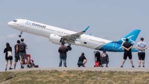 People look on as an Air Transat plane takes off at Trudeau in Montreal on June 11, 2023. THE CANADIAN PRESS/Graham Hughes
