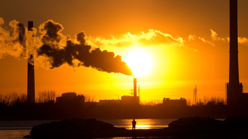 A man photographs the setting sun as powerplant smokestacks battle freezing temperatures in Toronto on Friday, January 16, 2015. THE CANADIAN PRESS/Frank Gunn

