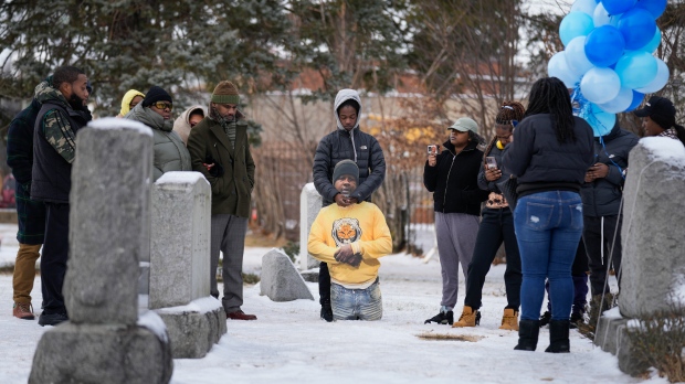 Timere Jones, centre, carries a life-sized picture of his brother, Jameek Lowery, as he and other family and friends visit his grave in Garfield, N.J., Thursday, Jan. 18, 2024. (AP Photo/Seth Wenig)