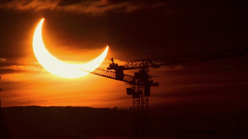 An annular solar eclipse rises over construction cranes and the Peace Tower on Parliament Hill in Ottawa on Thursday, June 10, 2021. A total solar eclipse is a rare celestial event that always generates excitement, but next month's version is expected to be unusually spectacular. THE CANADIAN PRESS/Sean Kilpatrick