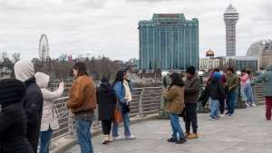 Tourists on the American side of Niagara Falls take photos in Niagara Falls, N.Y. on Friday, March 29, 2024. Ontario's Niagara Region has declared a state of emergency as it readies to welcome up to a million visitors for the solar eclipse in early April. THE CANADIAN PRESS/Carlos Osorio
