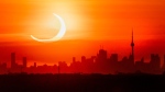 An annular solar eclipse rises over the skyline of Toronto on Thursday, June 10, 2021. (Frank Gunn / The Canadian Press)