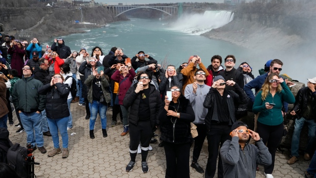 People gather to watch the total solar eclipse from Niagara Falls, Ontario, Monday, April 8, 2024. (AP Photo/Matt Rourke)