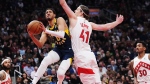 Indiana Pacers guard Tyrese Haliburton (0) drives to the net as Toronto Raptors forward Kelly Olynyk (41) defends during first half NBA basketball action in Toronto on Tuesday, April 9, 2024. THE CANADIAN PRESS/Nathan Denette