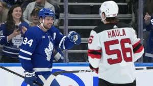 New Jersey Devils left wing Erik Haula (56) looks on as Toronto Maple Leafs centre Auston Matthews (34) celebrates his goal during first period NHL hockey action in Toronto, Thursday, April 11, 2024. THE CANADIAN PRESS/Nathan Denette