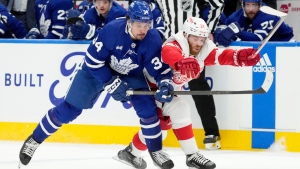 Toronto Maple Leafs centre Auston Matthews (34) and Detroit Red Wings left wing J.T. Compher (37) vie for control of the puck during second period NHL hockey in Toronto, Saturday, April 13, 2024. THE CANADIAN PRESS/Frank Gunn