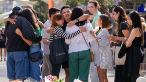 A group of people react after placing flowers as a tribute near a crime scene at Bondi Junction in Sydney, Monday, April 15, 2024. (AP Photo/Mark Baker)