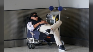 FILE - A traveler takes a nap as he waits for a ride outside Miami International Airport, Friday, July 1, 2022, in Miami. The Gallup survey, released Monday, April 15, 2024, says that a majority of Americans say they would feel better if they could have more sleep. But in the U.S., where the ethos of grinding and pulling yourself up by your own bootstraps is ubiquitous, getting enough sleep can seem like a dream. (AP Photo/Wilfredo Lee, File)