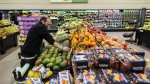A worker stocks shelves of produce at a grocery store In Toronto on Friday, Feb. 2, 2024. Inflation on groceries continued to slow in March, rising just 1.9 per cent compared with a year earlier. THE CANADIAN PRESS/Cole Burston