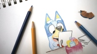 Colored pencils sit around a drawing of "Bluey" the Australian kids' television program character on a sketch pad Friday, April 19, 2024, in Phoenix, Ariz. (AP Photo/Cheyanne Mumphrey)
