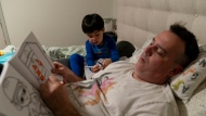 Scott Quinn and his 4-year-old son, Ethan, work on coloring books in a bed in Concord, Calif., Wednesday, Nov. 1, 2023. (AP Photo/Jae C. Hong)