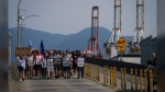 Federal Labour Minister Seamus O'Regan says he's appointed an Industrial Inquiry Commission to dig deeper into the underlying causes of B.C.'s port strike last summer. Striking International Longshore and Warehouse Union Canada workers march to a rally as gantry cranes used to load and unload cargo containers from ships sit idle at port, in Vancouver, B.C., Thursday, July 6, 2023. THE CANADIAN PRESS/Darryl Dyck