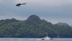 A Malaysian Maritime Enforcement Agency speedboat patrols while a Royal Malaysian Navy helicopter flies over the waters off the coast of Langkawi Island, Malaysia Thursday, May 28, 2015. (AP Photo/Vincent Thian) 