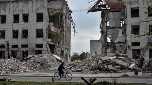 FILE - A local woman rides a bicycle on April 18, 2024, in front of a building destroyed by a Russian airstrike in the frontline town of Orikhiv, Ukraine. (Andriy Andriyenko / AP Photo)