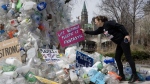 Activist Dianne Peterson places a sign on a public art installation outside a United Nations conference on plastics, Tuesday, April 23, 2024 in Ottawa. THE CANADIAN PRESS/Adrian Wyld