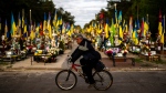 A man rides a bicycle past the tombs of Ukrainian soldiers killed during the war, at Lisove cemetery in Kyiv, Ukraine, Tuesday, April 23, 2024. (AP Photo/Francisco Seco) 