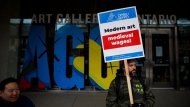 Art Gallery of Ontario employees and OPSEU union members wave placards on a picket line as they stage a strike outside the AGO in Toronto, Tuesday, March 26, 2024. THE CANADIAN PRESS/Cole Burston 