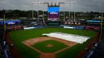 Members of the grounds crew remove the tarp from the field during a rain delay in a baseball game between the Kansas City Royals and the Toronto Blue Jays Thursday, April 25, 2024, in Kansas City, Mo. (AP Photo/Charlie Riedel)