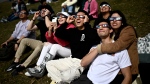 FILE - People wear solar eclipse glasses as they observe the partial phase of a total solar eclipse, in Kingston, Ont., Monday, April 8, 2024. THE CANADIAN PRESS/Justin Tang 