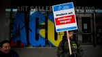 FILE - Art Gallery of Ontario employees and OPSEU union members wave placards on a picket line as they stage a strike outside the AGO in Toronto, Tuesday, March 26, 2024. THE CANADIAN PRESS/Cole Burston 