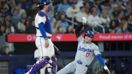 Los Angeles Dodgers designated hitter Shohei Ohtani (17) slides safe past Toronto Blue Jays catcher Danny Jansen (9) at home plate to score a run during third inning Interleague MLB baseball action in Toronto on Friday, April 26, 2024. THE CANADIAN PRESS/Nathan Denette