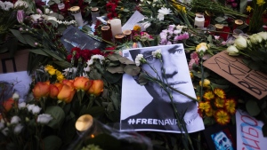 A photo of Russian opposition leader Alexei Navalny lays between flowers and candles near the Russian emabssy during a protest in Berlin, Sunday, Feb. 18, 2024. (AP Photo/Markus Schreiber)