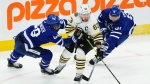 Boston Bruins' Brad Marchand (63) is checked by Toronto Maple Leafs' William Nylander (88) and John Tavares (91) during first period action in Game 4 of an NHL hockey Stanley Cup first-round playoff series in Toronto on Saturday, April 27, 2024. THE CANADIAN PRESS/Nathan Denette