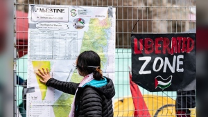 A pro-Palestinian activist looks at a map of Palestine taped to the fencing around their encampment on McGill University's campus in Montreal, Monday, April 29, 2024. The University of Ottawa is warning pro-Palestinian student activists who are following the lead of some American and Canadian post-secondary students and setting up camp today on university property that their protest can face serious consequences.THE CANADIAN PRESS/Christinne Muschi
