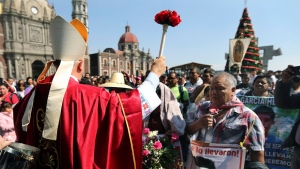The Bishop of Chilpancingo, Guerrero state, Salvador Rangel, sprinkles holy water over family members of 43 missing students from the Isidro Burgos rural teachers college, outside the Basilica of Guadalupe in Mexico City, Thursday, Dec. 26, 2019. (AP Photo/Marco Ugarte)