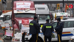 A parliamentary committee reviewing Ottawa’s use of the Emergencies Act has set a date to get back to drafting a report that was initially due in December 2022. Police officers keep an eye on protest trucks, in Ottawa, Thursday, Feb. 17, 2022. THE CANADIAN PRESS/Adrian Wyld

